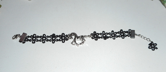 Originele armband met zilverkleurig metalen paard op zwart kant