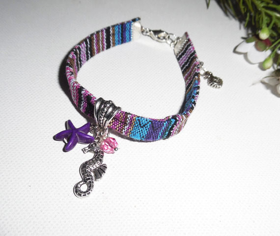 Kleurrijke stoffen armband met kwastjes van zeepaardjes en paarse zeesterren