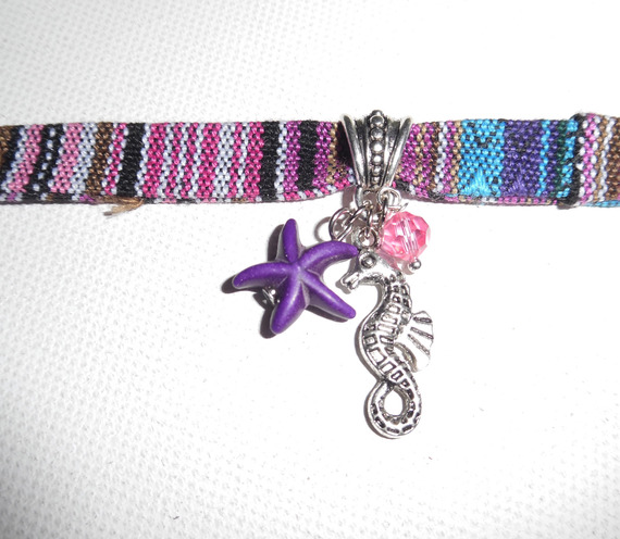 Kleurrijke stoffen armband met kwastjes van zeepaardjes en paarse zeesterren