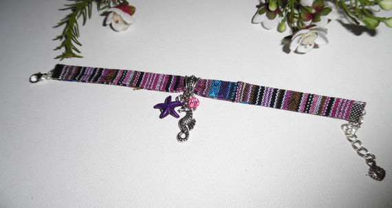 Kleurrijke stoffen armband met kwastjes van zeepaardjes en paarse zeesterren
