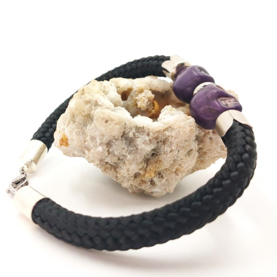 Dubbele schedel en gekruiste botten armband met paarse stenen op zwart touw