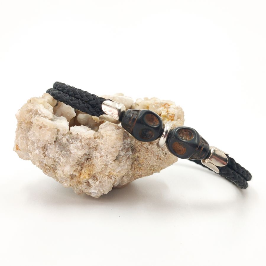 Dubbele schedel en gekruiste botten armband met zwarte stenen op dubbel touw
