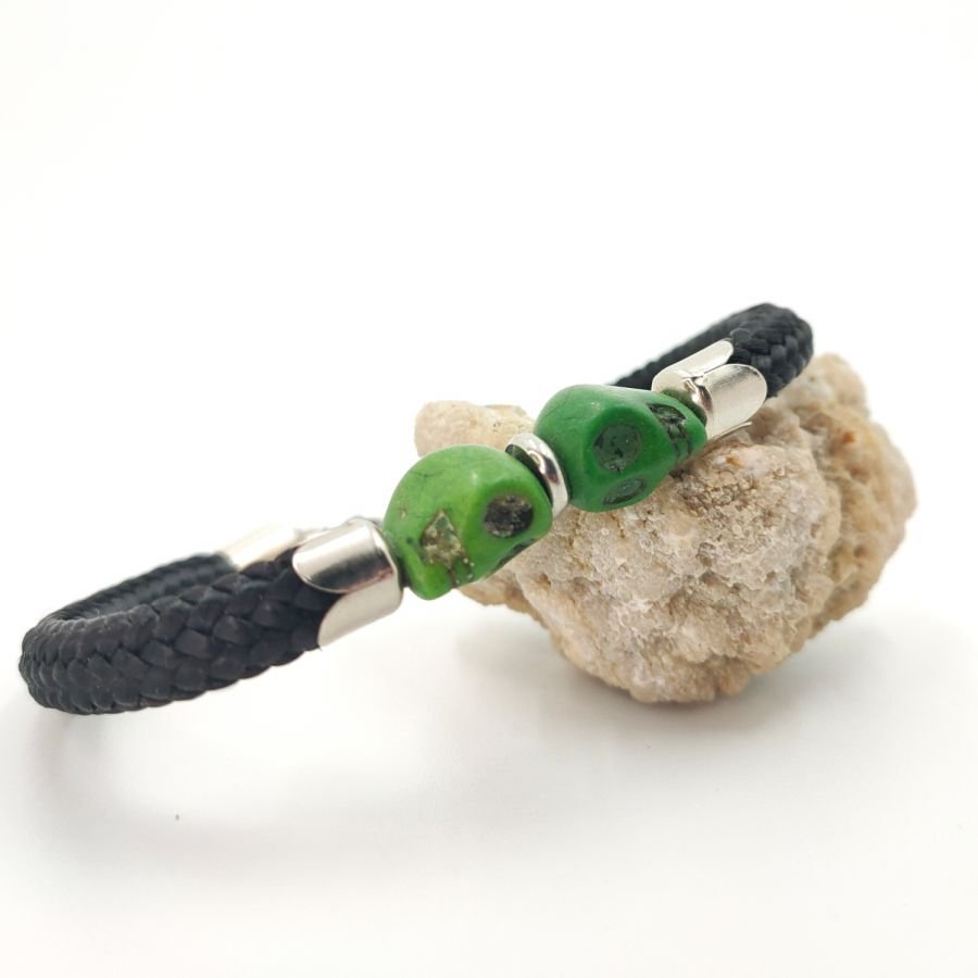 Dubbele schedel en gekruiste botten armband met groene stenen op zwart touw