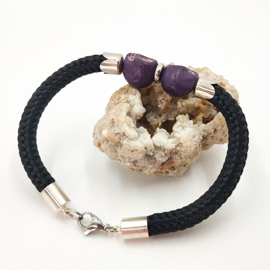 Dubbele schedel en gekruiste botten armband met paarse stenen op zwart touw