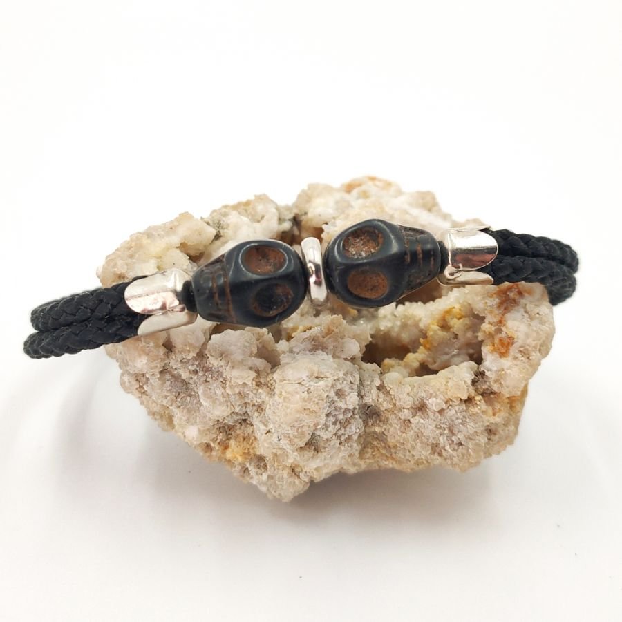 Dubbele schedel en gekruiste botten armband met zwarte stenen op dubbel touw
